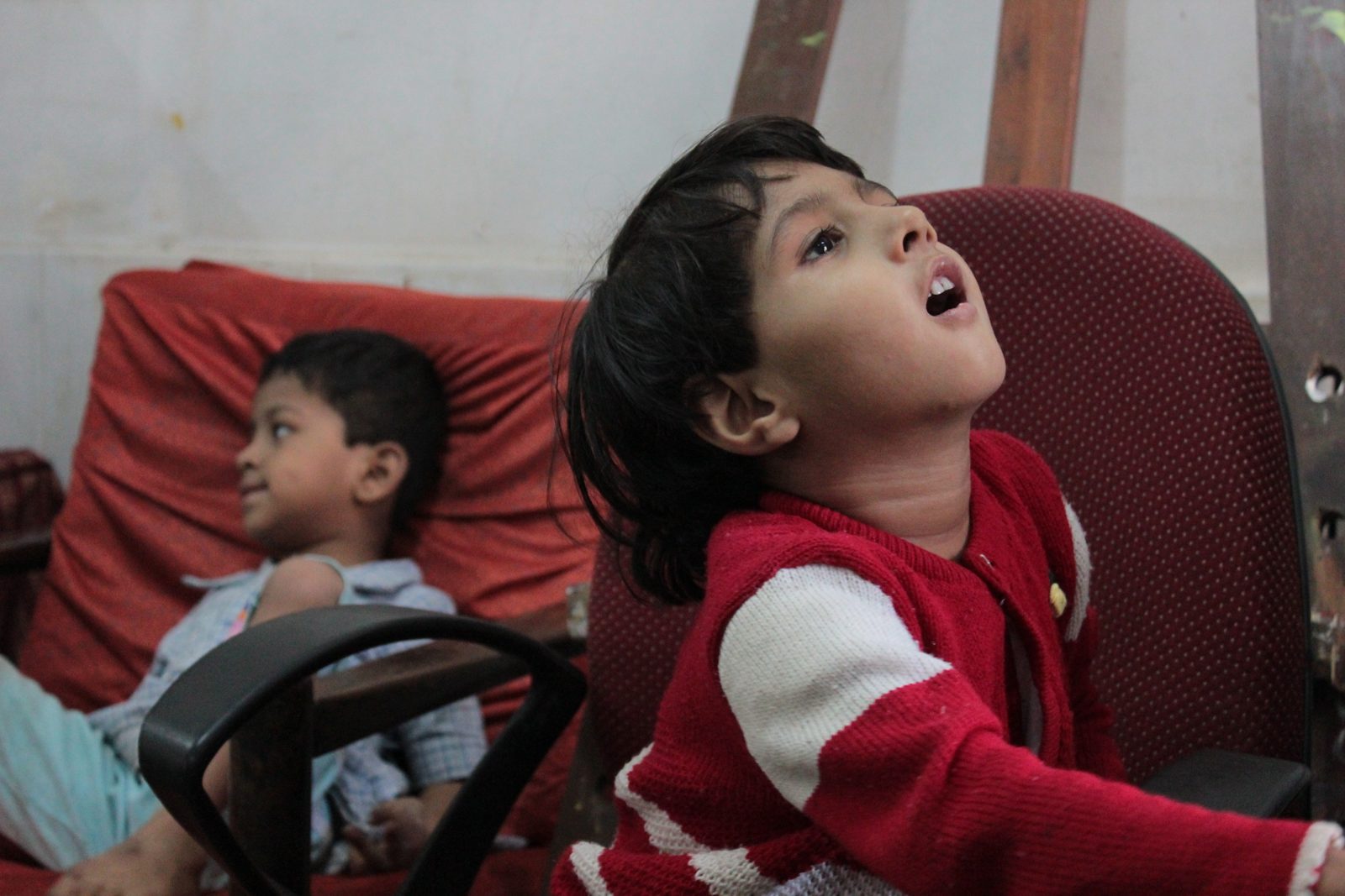 A young student in a red sweater laughing with delight during a dance workshop