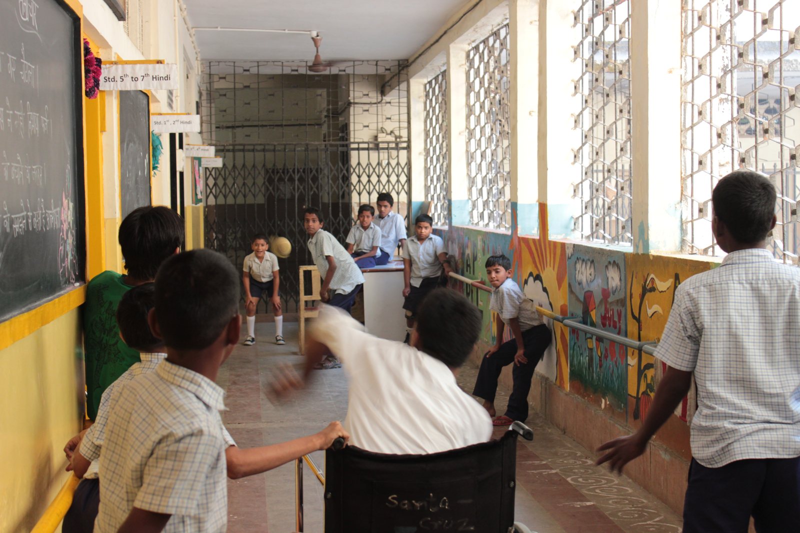Students playing a game of cricket together in the school hallway
