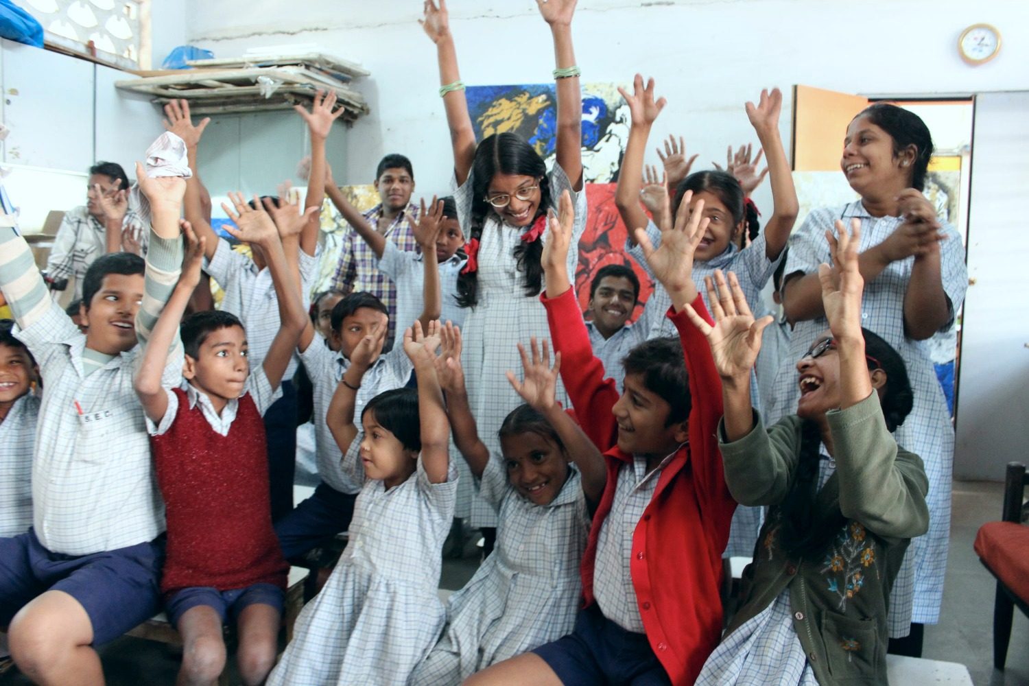 A classroom of students cheering with their arms raised in the air