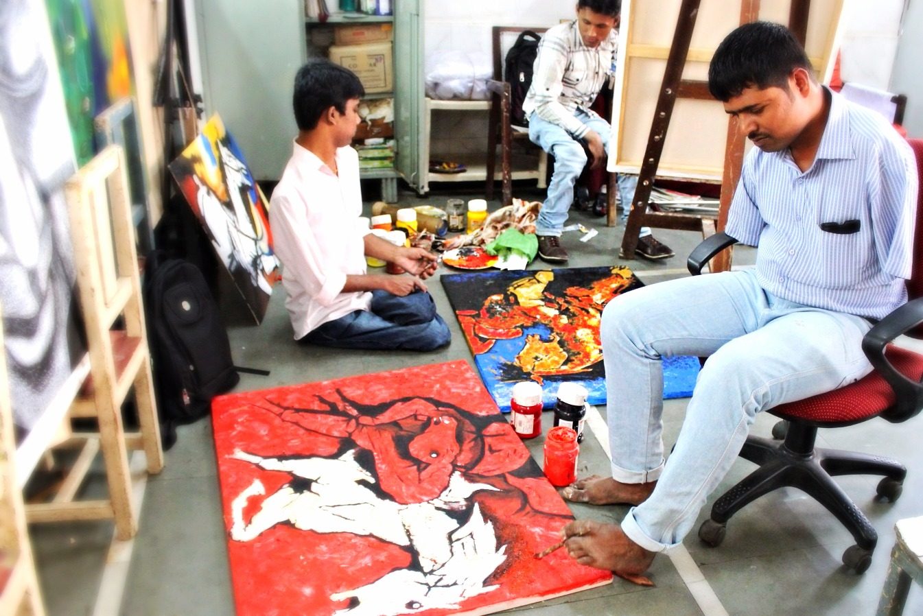 Students and staff working on large colorful paintings in the art room