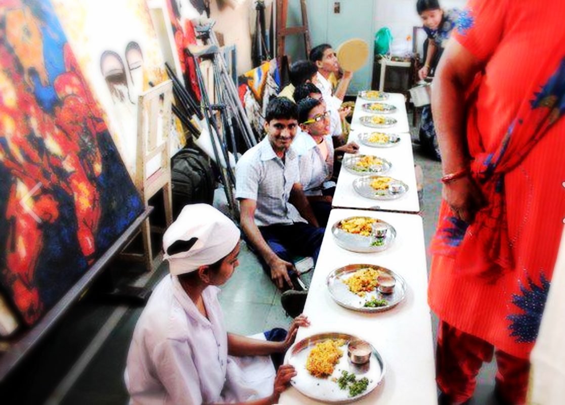 Students seated at a long table being served fresh hot meals